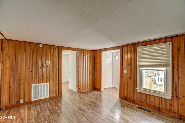 spare room with wooden walls and light hardwood / wood-style flooring