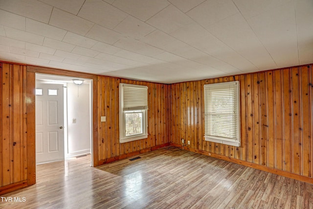 empty room featuring wood walls and light wood-type flooring