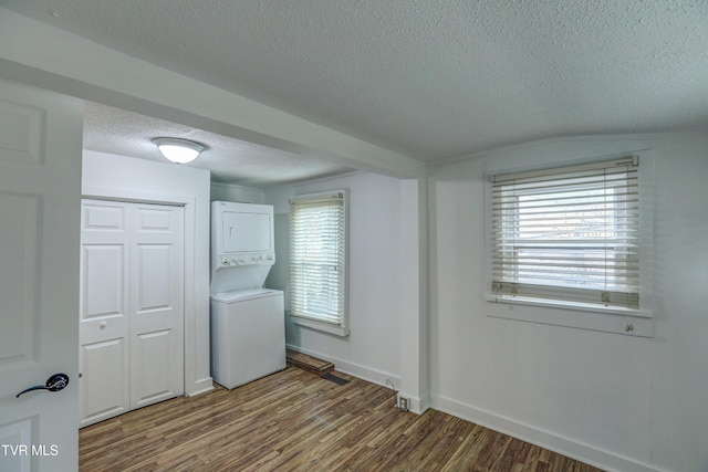 laundry area with stacked washing maching and dryer, wood-type flooring, and a textured ceiling