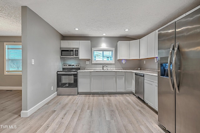 kitchen with white cabinets, plenty of natural light, light wood-type flooring, and stainless steel appliances