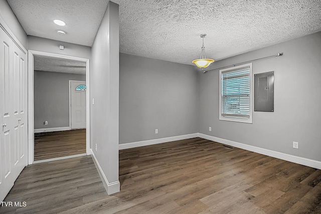 empty room featuring electric panel, dark wood-type flooring, and a textured ceiling