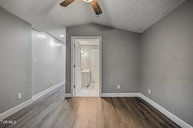 unfurnished bedroom featuring lofted ceiling, ceiling fan, a textured ceiling, and light wood-type flooring