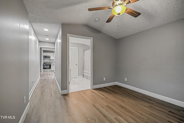 interior space with lofted ceiling, ceiling fan, light hardwood / wood-style floors, and a textured ceiling