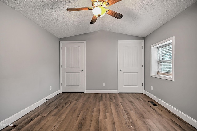 unfurnished bedroom with a textured ceiling, dark hardwood / wood-style floors, vaulted ceiling, and ceiling fan