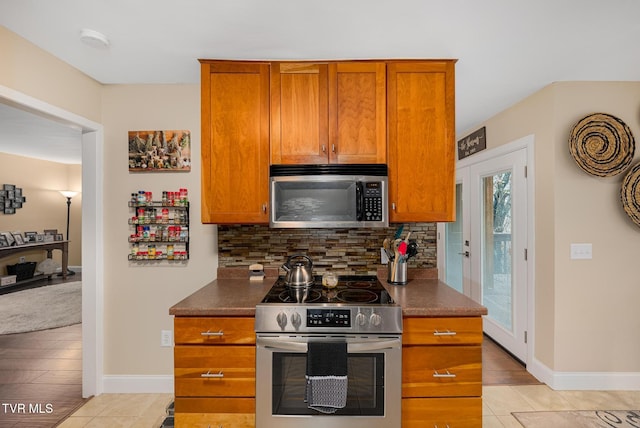 kitchen with decorative backsplash, appliances with stainless steel finishes, and light hardwood / wood-style flooring