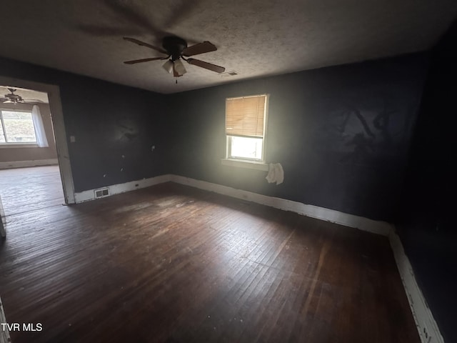 spare room featuring ceiling fan, a healthy amount of sunlight, and dark hardwood / wood-style floors