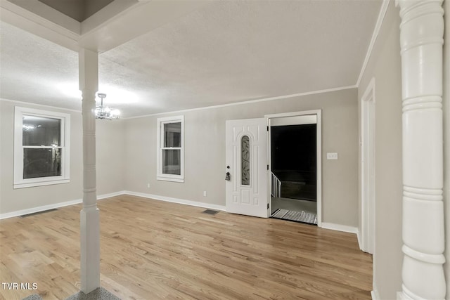 spare room with hardwood / wood-style floors, a textured ceiling, an inviting chandelier, and ornamental molding