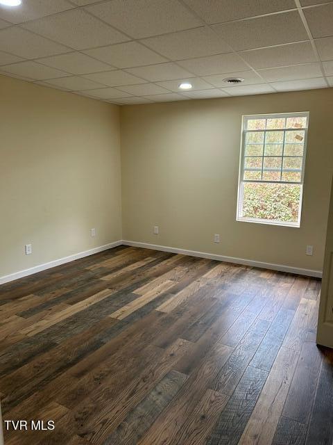 spare room featuring a drop ceiling and dark hardwood / wood-style flooring