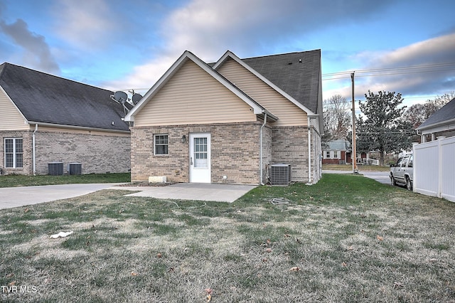 rear view of property featuring central air condition unit, a patio area, and a lawn