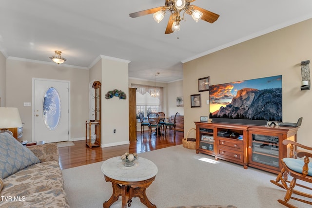 living room featuring hardwood / wood-style floors, ceiling fan with notable chandelier, and crown molding