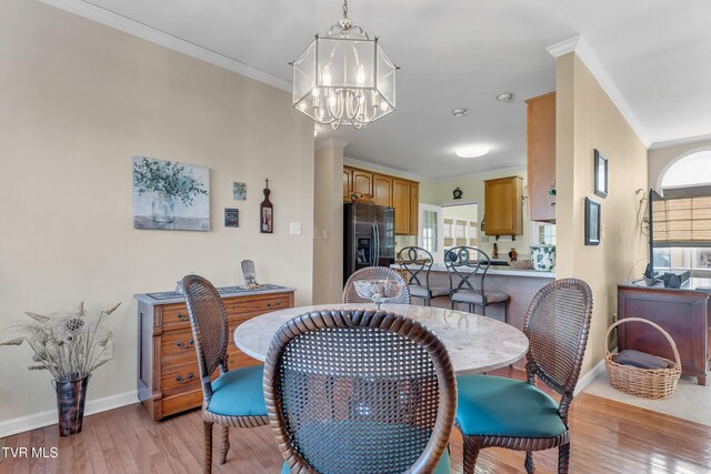 dining space with a notable chandelier, light hardwood / wood-style floors, and ornamental molding