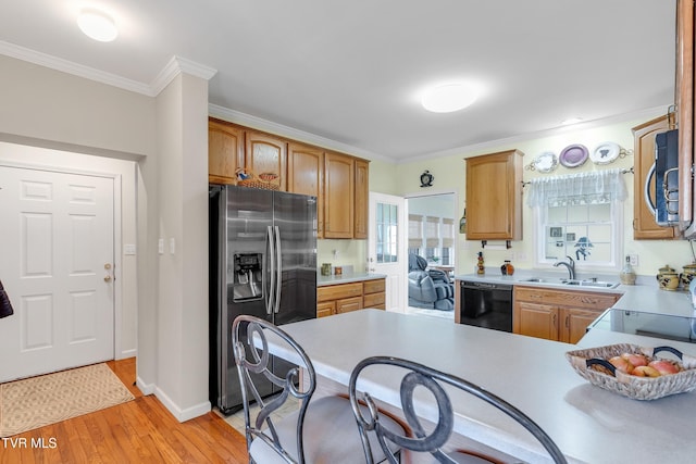 kitchen with kitchen peninsula, appliances with stainless steel finishes, crown molding, sink, and light hardwood / wood-style floors