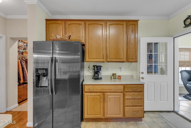 kitchen with light hardwood / wood-style floors, stainless steel fridge, and ornamental molding