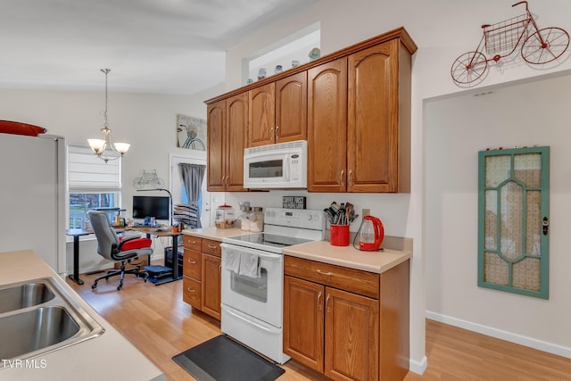 kitchen featuring light wood-type flooring, white appliances, vaulted ceiling, decorative light fixtures, and a notable chandelier