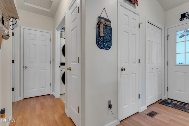 foyer entrance featuring light hardwood / wood-style flooring and stacked washer and clothes dryer