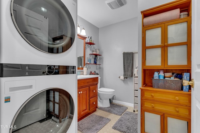 bathroom featuring vanity, toilet, and stacked washer / dryer