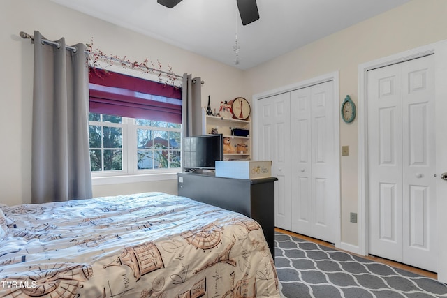 bedroom featuring wood-type flooring, ceiling fan, and multiple closets