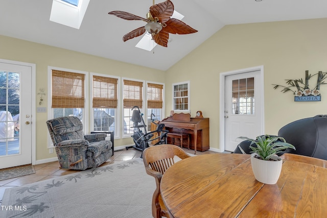 tiled dining room with ceiling fan and vaulted ceiling with skylight