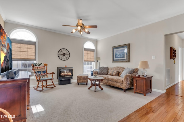 living room with light hardwood / wood-style flooring, a wealth of natural light, crown molding, and ceiling fan