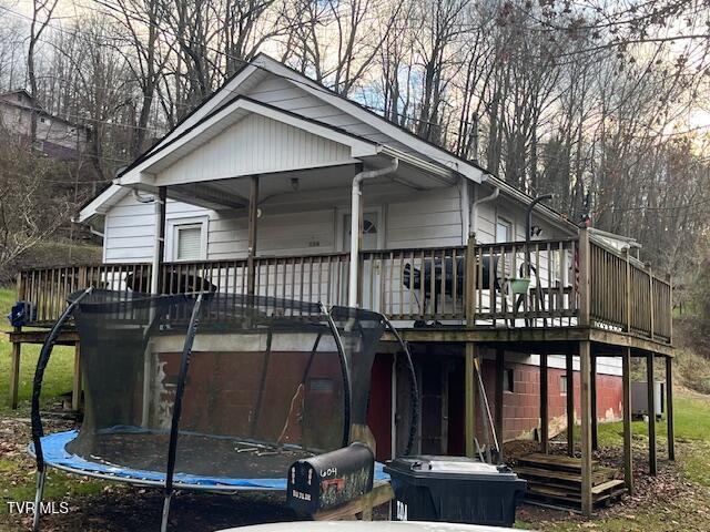 back of property with a deck and a trampoline