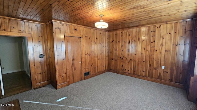 empty room with carpet flooring, wood walls, and wooden ceiling