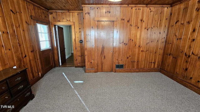 unfurnished bedroom featuring wood ceiling, light carpet, and wooden walls