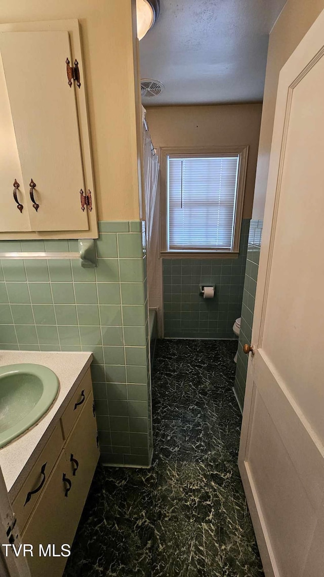 full bathroom featuring toilet, vanity, shower / tub combo with curtain, and tile walls