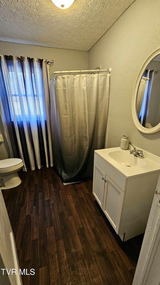 bathroom with vanity, a textured ceiling, hardwood / wood-style flooring, and toilet