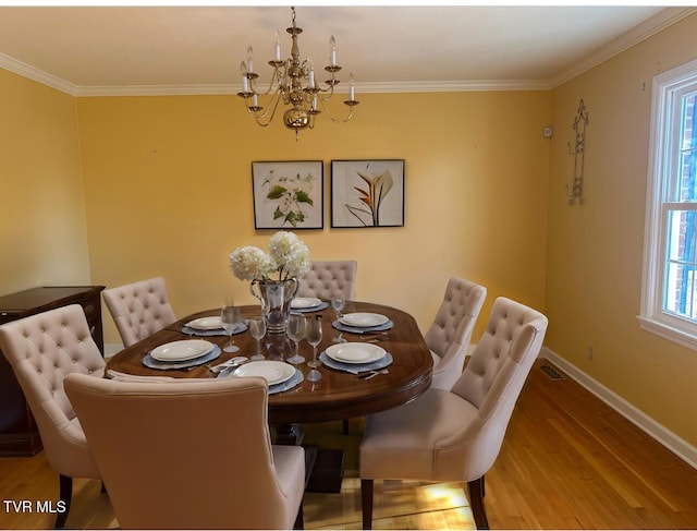 dining space featuring hardwood / wood-style flooring, a healthy amount of sunlight, crown molding, and an inviting chandelier