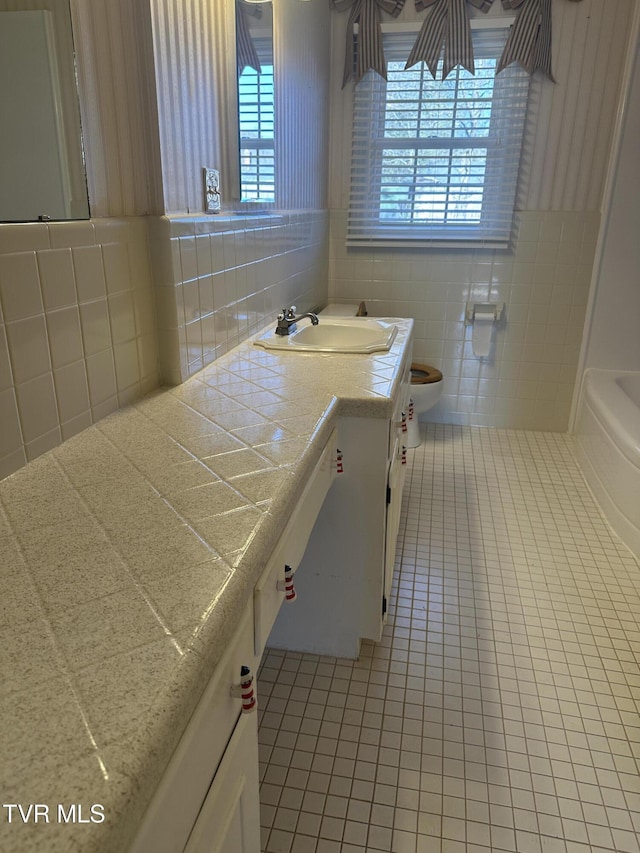 bathroom with tile patterned floors, plenty of natural light, and tile walls