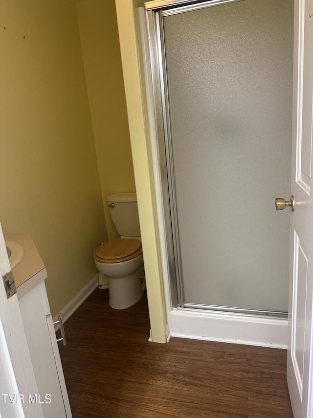 bathroom with hardwood / wood-style floors, vanity, toilet, and a shower with door