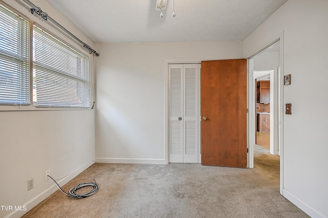 unfurnished bedroom with a textured ceiling, light carpet, and a closet