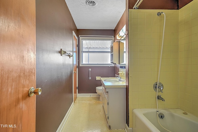 full bathroom with vanity, toilet, a textured ceiling, and tiled shower / bath combo