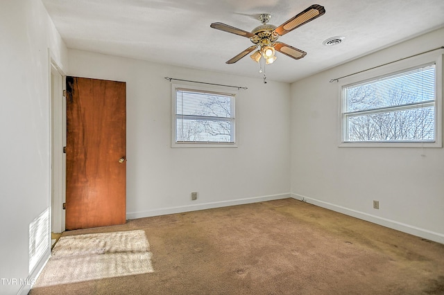 carpeted empty room with ceiling fan and a wealth of natural light