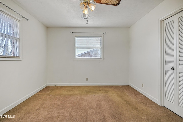 unfurnished bedroom with light carpet, a textured ceiling, a closet, and ceiling fan