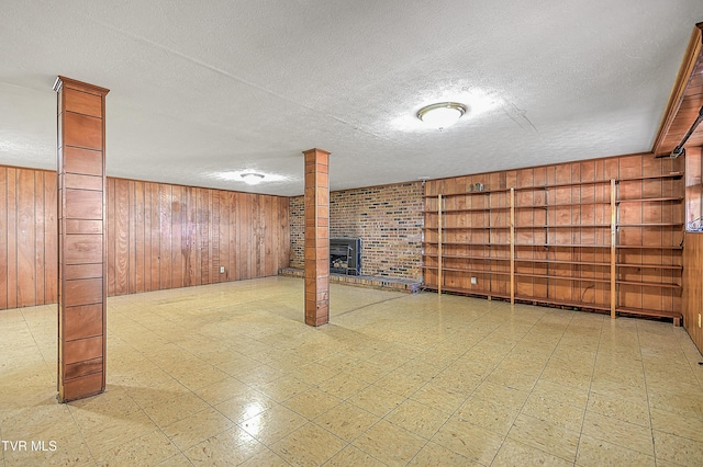 basement featuring wood walls, a wood stove, a textured ceiling, and built in features