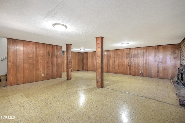 basement featuring a textured ceiling, a wood stove, and wooden walls