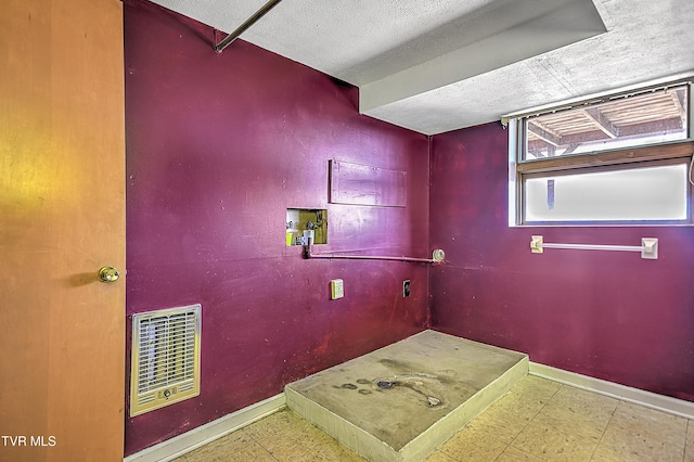 interior space with washer hookup, a textured ceiling, and heating unit