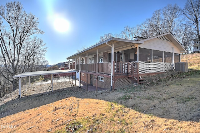 view of side of home featuring a sunroom, a carport, and central air condition unit