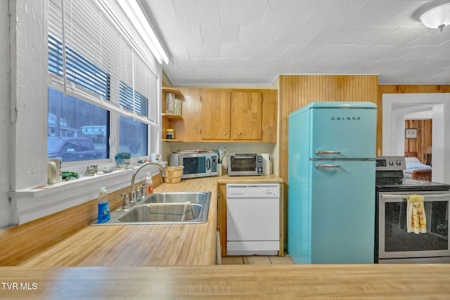 kitchen featuring appliances with stainless steel finishes, wood walls, and sink