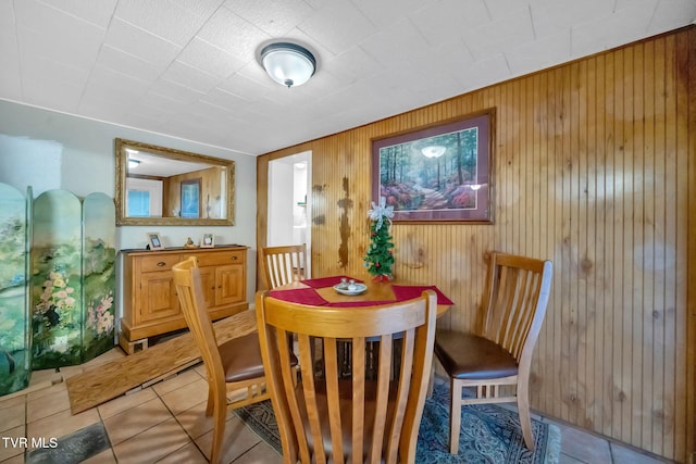 tiled dining space featuring wood walls