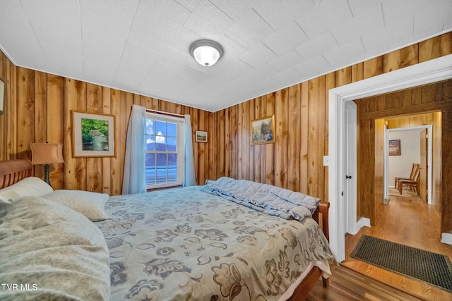 bedroom with wooden walls and hardwood / wood-style floors