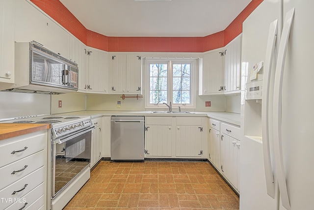 kitchen featuring white appliances, white cabinetry, and sink