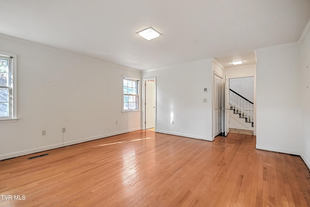 spare room featuring ornamental molding, light wood-type flooring, and a healthy amount of sunlight