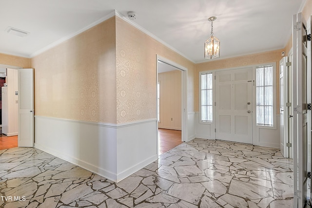 entryway with light hardwood / wood-style floors, ornamental molding, and a chandelier