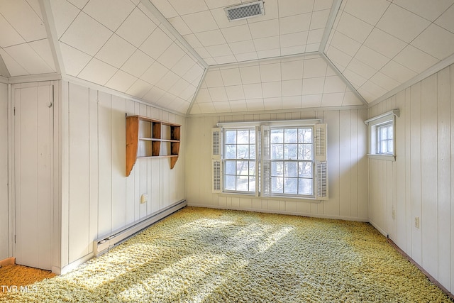 empty room with light carpet, a wealth of natural light, baseboard heating, and wooden walls