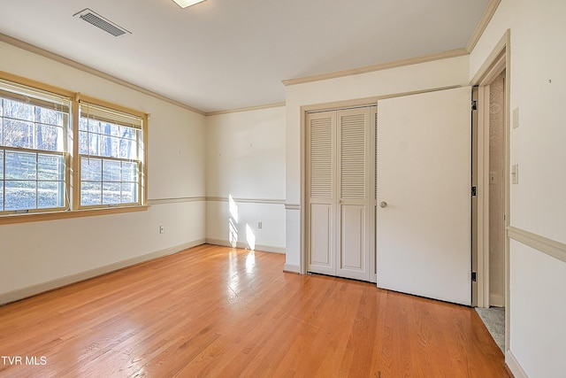 unfurnished bedroom with crown molding, a closet, and light hardwood / wood-style floors