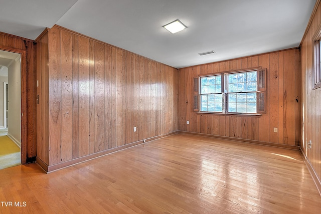 empty room with wood walls and light hardwood / wood-style flooring