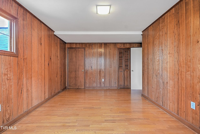 spare room featuring light hardwood / wood-style flooring and wood walls