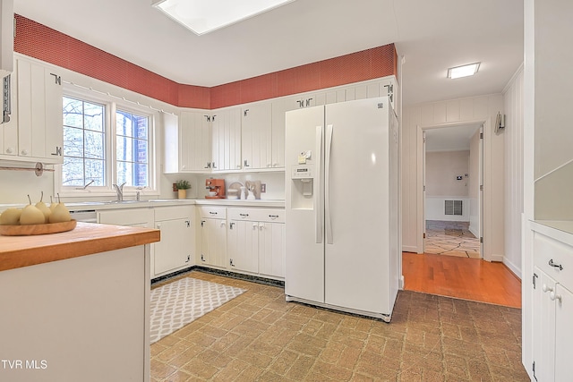 kitchen featuring white refrigerator with ice dispenser, white cabinets, light hardwood / wood-style flooring, and sink